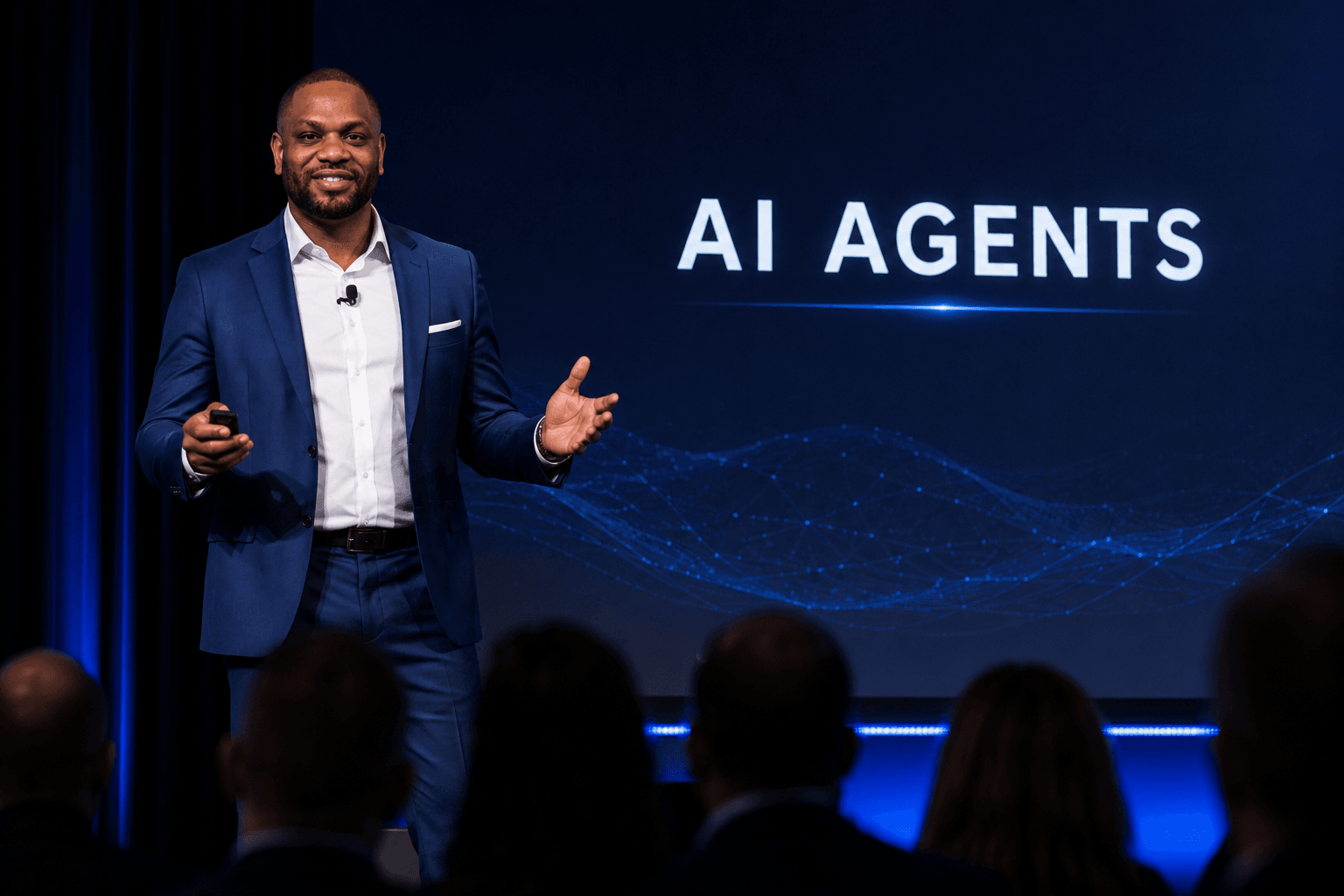Yves Hughes speaking on stage in front of an audience, with 'AI Agents' on the screen behind him
